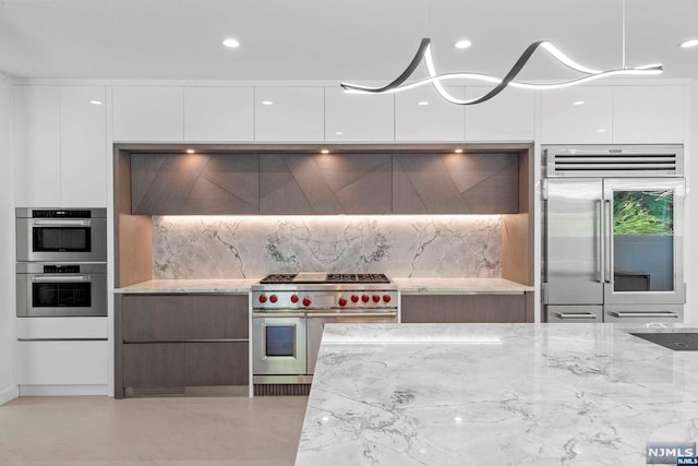 kitchen featuring backsplash, high end appliances, white cabinetry, and light stone counters