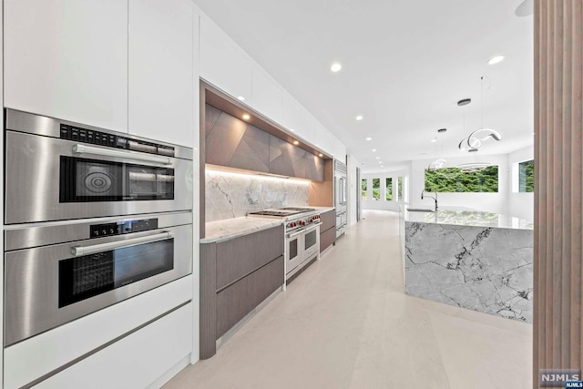 kitchen featuring decorative backsplash, a wealth of natural light, white cabinets, and appliances with stainless steel finishes