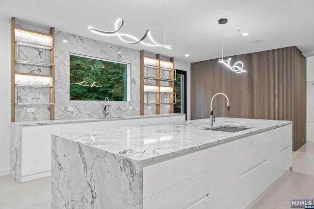 kitchen featuring sink, white cabinetry, and an island with sink