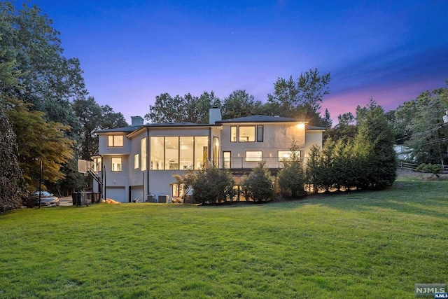 back house at dusk featuring a yard