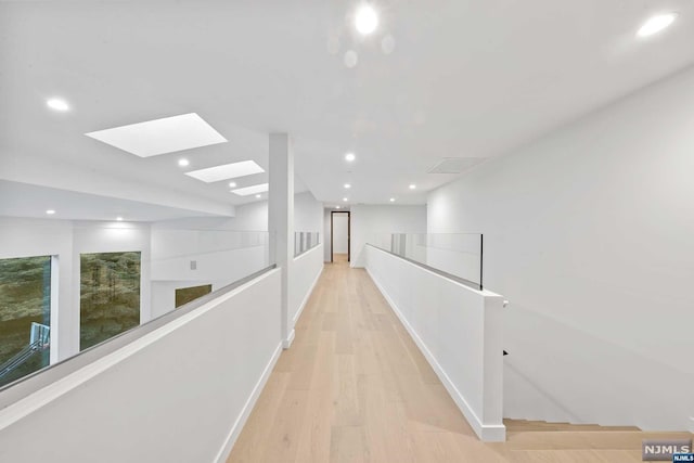 hall with light hardwood / wood-style floors and a skylight