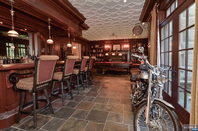 wine cellar with french doors, a textured ceiling, pool table, crown molding, and wood walls