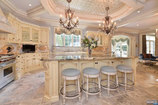 kitchen featuring cream cabinets, stainless steel range, and a center island with sink