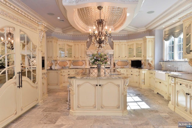 kitchen featuring a center island, tasteful backsplash, light stone counters, crown molding, and pendant lighting