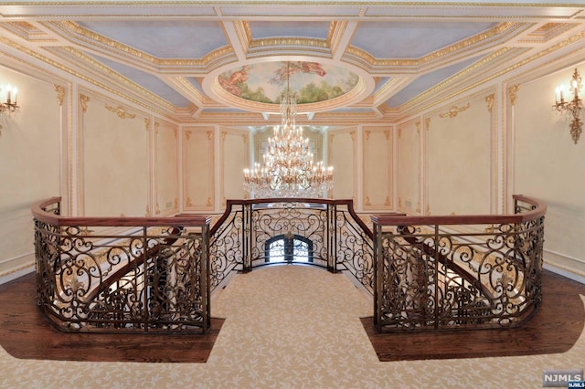 stairway with a chandelier, crown molding, and coffered ceiling