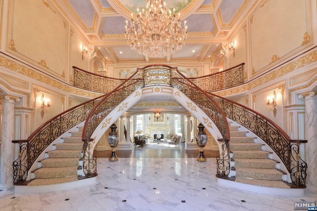 foyer entrance with a chandelier, a towering ceiling, ornate columns, and crown molding