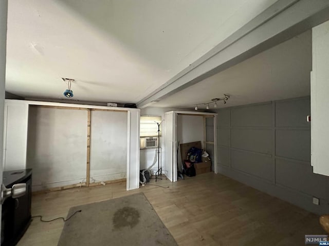 basement featuring light wood-type flooring and rail lighting