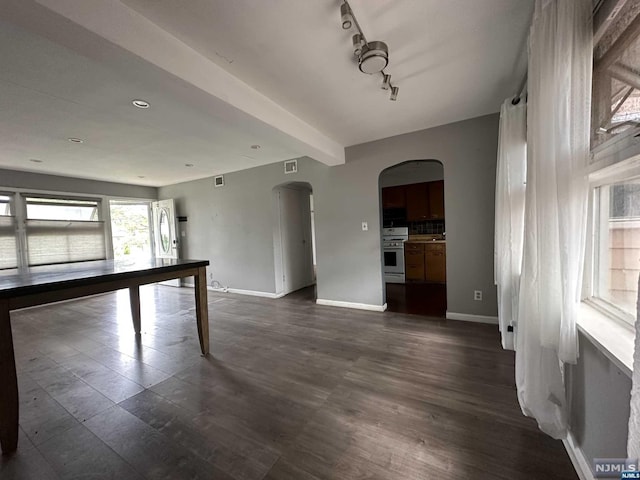 unfurnished room featuring beamed ceiling, dark hardwood / wood-style flooring, and rail lighting