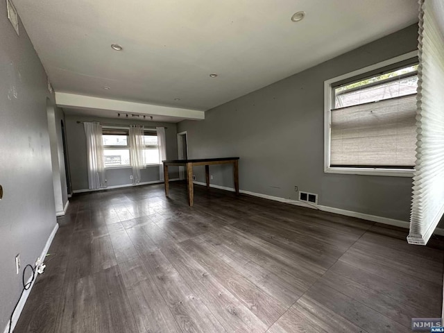 spare room with dark hardwood / wood-style flooring and plenty of natural light