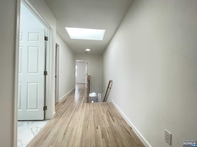 hall featuring light wood-type flooring and a skylight