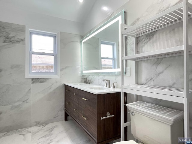 bathroom featuring vanity, toilet, and tile walls