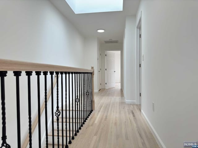 corridor featuring light hardwood / wood-style flooring and a skylight