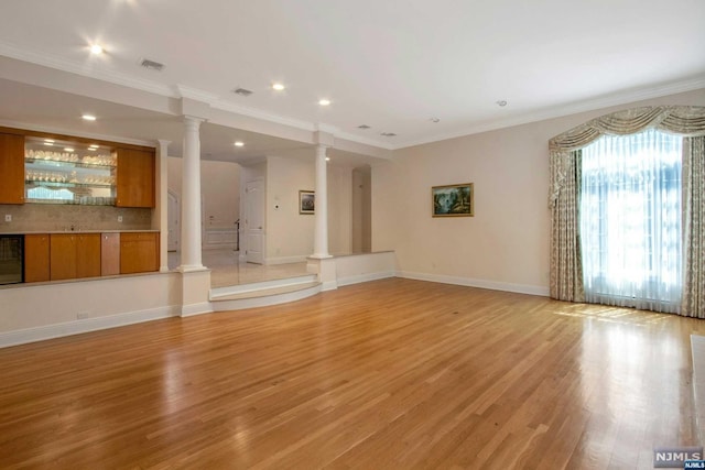 unfurnished living room featuring wine cooler, ornamental molding, and light wood-type flooring