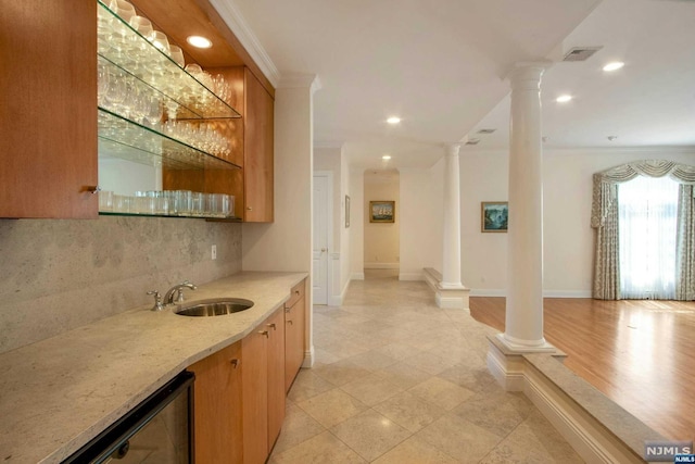 bar with light stone countertops, decorative backsplash, decorative columns, ornamental molding, and sink