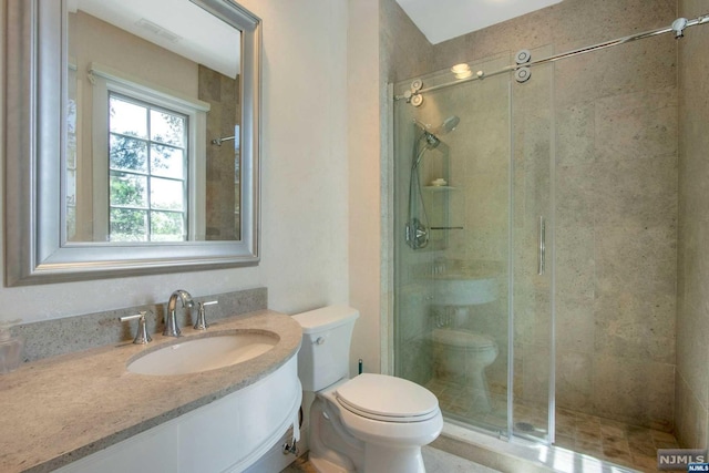 bathroom featuring toilet, vanity, and walk in shower