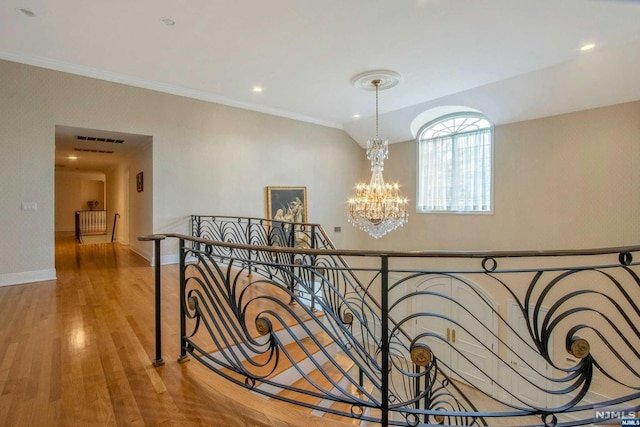 corridor featuring hardwood / wood-style floors, ornamental molding, and a chandelier