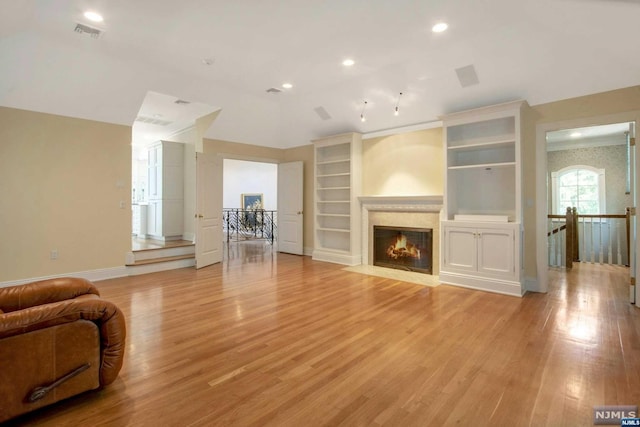 living room featuring built in shelves and light hardwood / wood-style floors