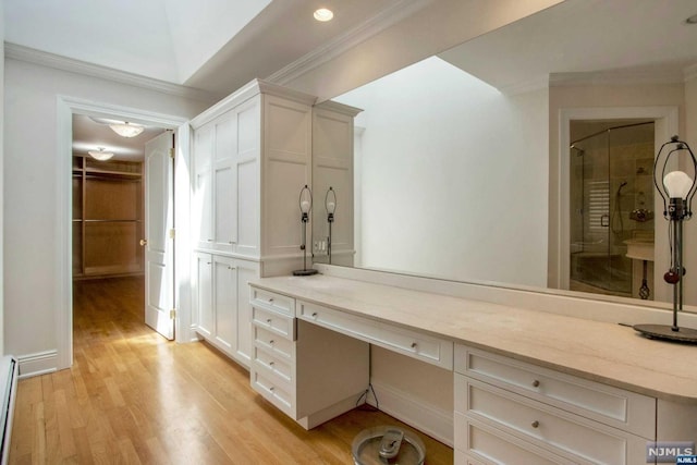 bathroom with hardwood / wood-style flooring, a tile shower, ornamental molding, and a baseboard heating unit