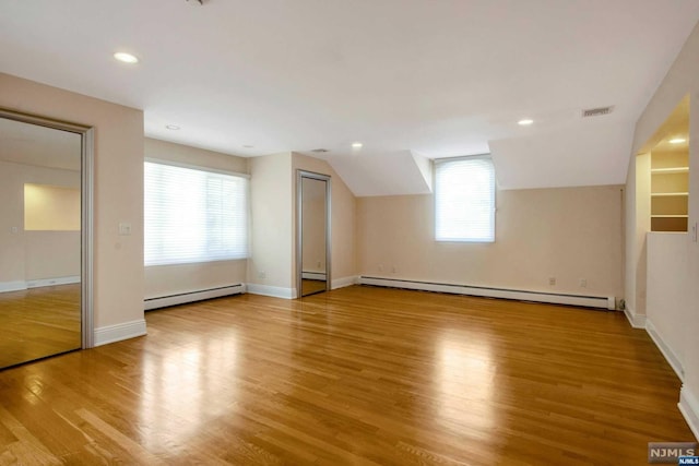 additional living space featuring light hardwood / wood-style floors, lofted ceiling, and a baseboard radiator