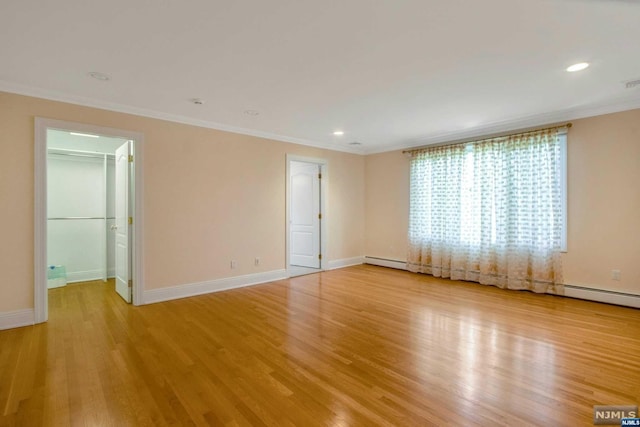 empty room with light wood-type flooring, baseboard heating, and crown molding