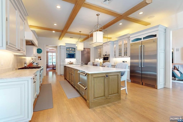 kitchen featuring white cabinetry, light stone counters, a spacious island, decorative light fixtures, and appliances with stainless steel finishes