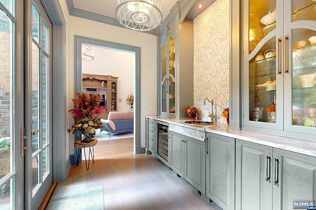 bar with light stone countertops, gray cabinets, light hardwood / wood-style flooring, and a healthy amount of sunlight