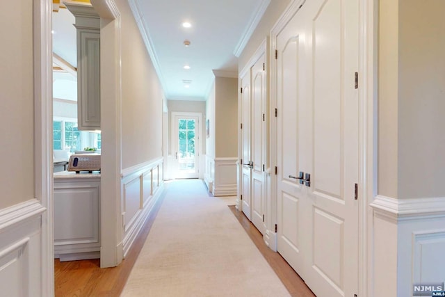 hallway with light wood-type flooring, a wealth of natural light, and crown molding