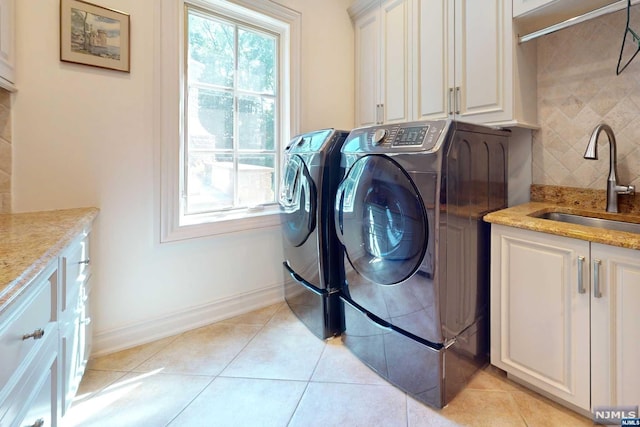 laundry room featuring washing machine and dryer, sink, light tile patterned floors, and cabinets