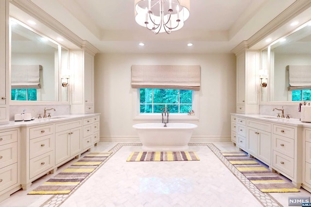 bathroom with a raised ceiling, vanity, and an inviting chandelier