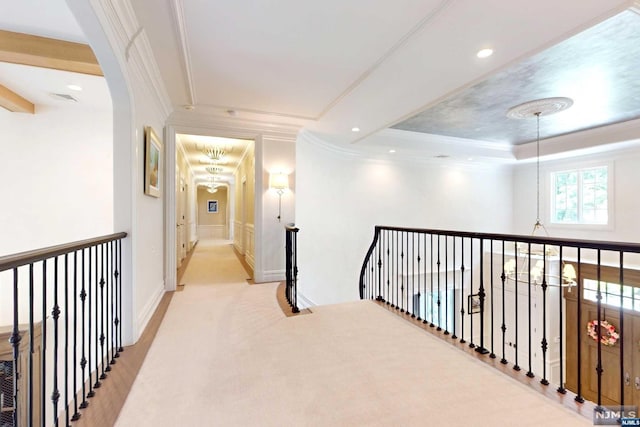 corridor with light colored carpet, a notable chandelier, and ornamental molding