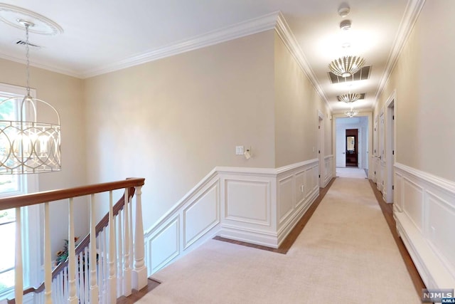 hallway with light carpet, crown molding, and an inviting chandelier