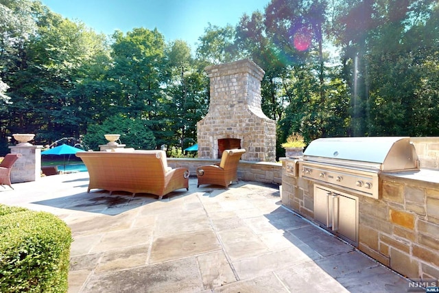 view of patio / terrace featuring an outdoor stone fireplace, grilling area, and exterior kitchen