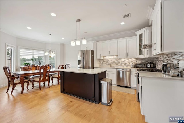 kitchen with white cabinetry, a center island, hanging light fixtures, stainless steel appliances, and light wood-type flooring