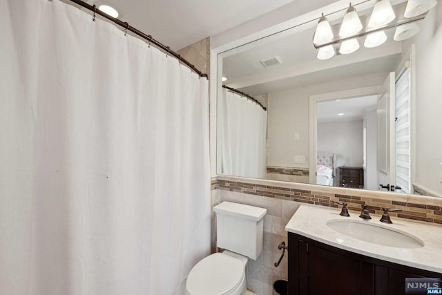 bathroom with vanity, tile walls, and toilet