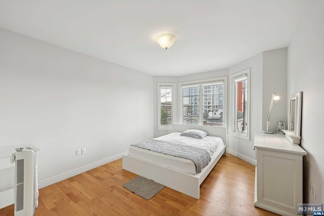 bedroom featuring heating unit and light hardwood / wood-style flooring