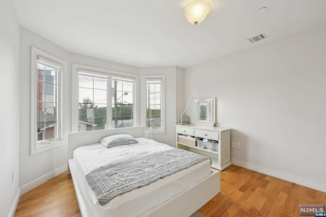 bedroom with multiple windows and light wood-type flooring