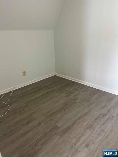 additional living space featuring lofted ceiling and dark hardwood / wood-style floors