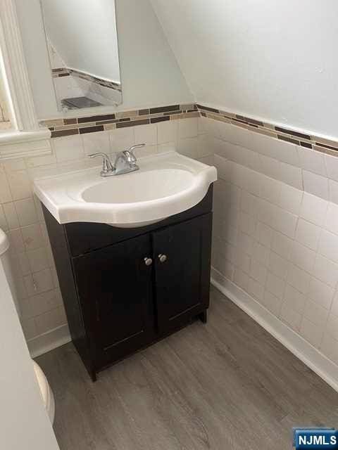 bathroom featuring toilet, vanity, tile walls, and hardwood / wood-style flooring