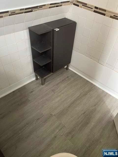 bathroom featuring wood-type flooring and tile walls