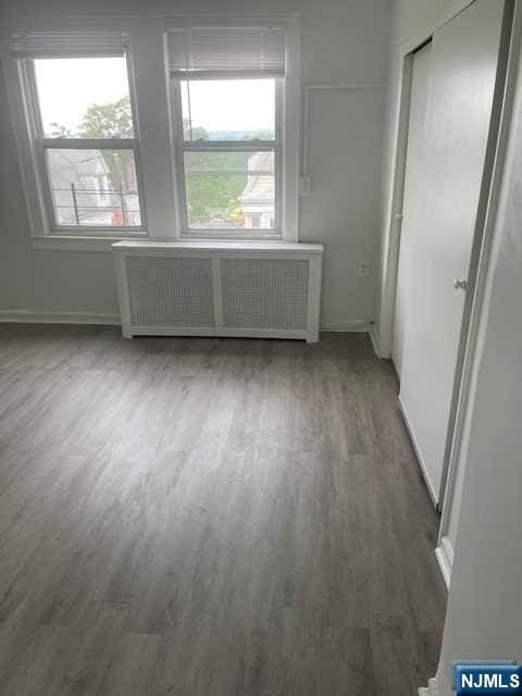 unfurnished room with radiator heating unit and dark wood-type flooring