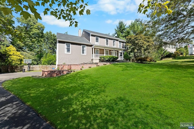 back of house featuring a lawn and covered porch