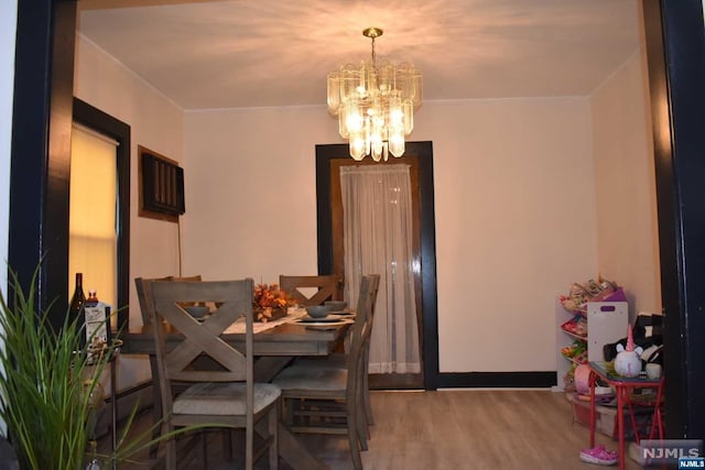 dining area featuring ornamental molding, wood-type flooring, and an inviting chandelier