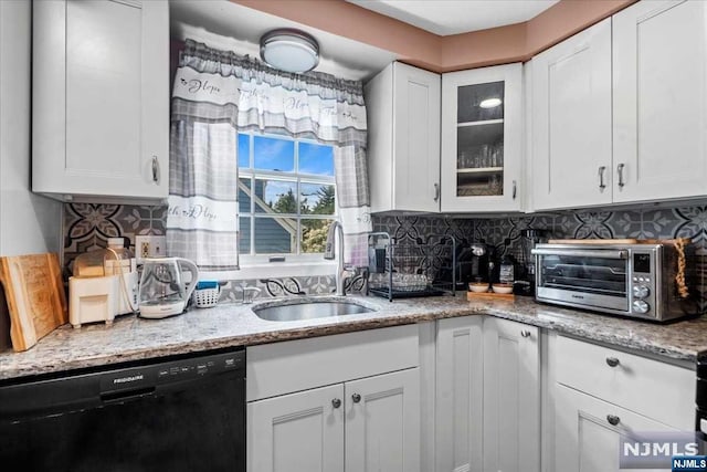 kitchen with backsplash, white cabinets, light stone counters, sink, and dishwasher