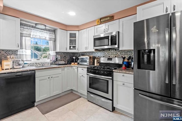 kitchen featuring white cabinetry, sink, light stone countertops, and appliances with stainless steel finishes