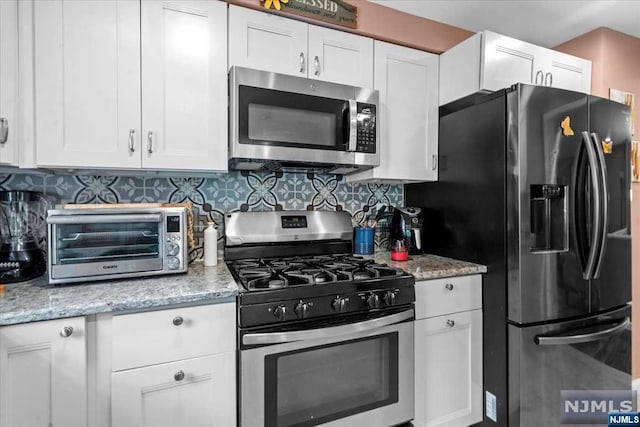 kitchen with decorative backsplash, white cabinetry, and appliances with stainless steel finishes