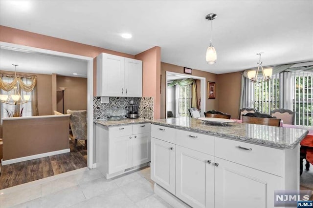 kitchen with white cabinets, light wood-type flooring, plenty of natural light, and hanging light fixtures