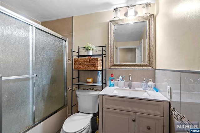 full bathroom with shower / bath combination with glass door, vanity, and toilet