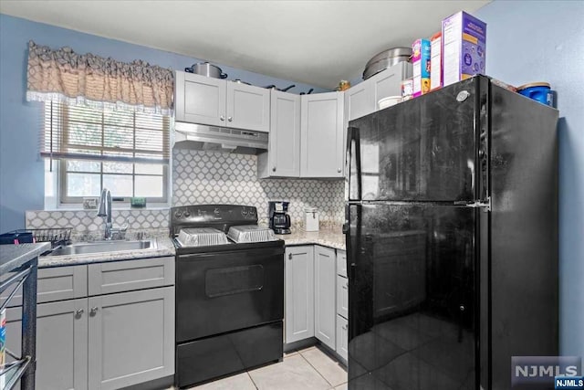 kitchen with black appliances, sink, light tile patterned floors, and backsplash