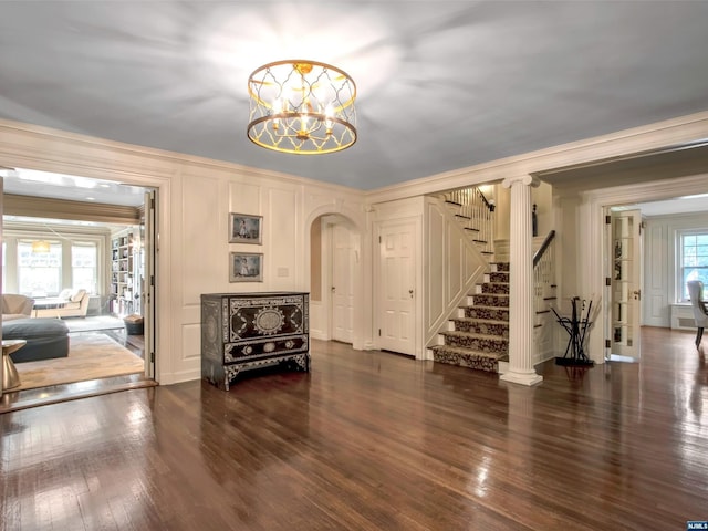 entrance foyer featuring ornamental molding, dark wood-type flooring, and a notable chandelier