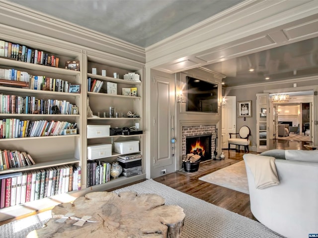 interior space featuring built in shelves, dark hardwood / wood-style flooring, ornamental molding, and a brick fireplace